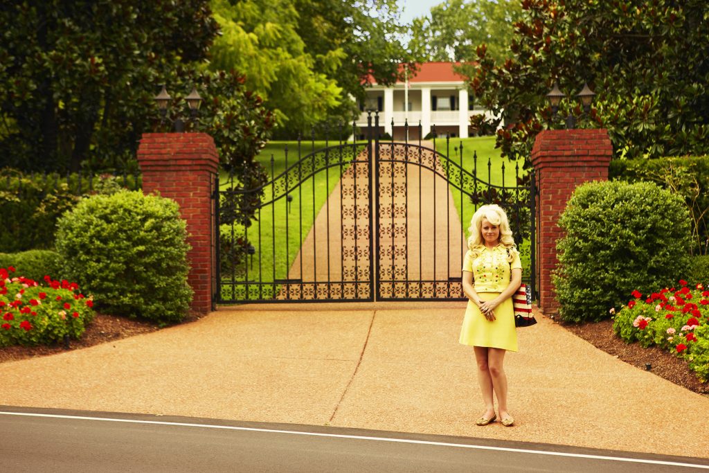 Self-portrait as Dolly Parton, standing outside Dolly’s house, Brentwood, Tennessee, 2011. ©️Alice Hawkins